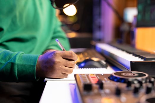 Songwriter taking notes on paper to compose a new soundtrack, making rhymes and mixing musical elements together. Artist composer creating new verses for a song in home studio. Close up. photo