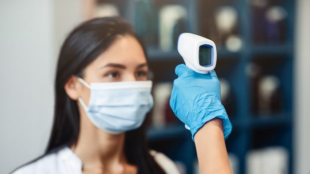 Temperature screening of customer. Worker holding ultrared heat scanner opposite woman client head photo