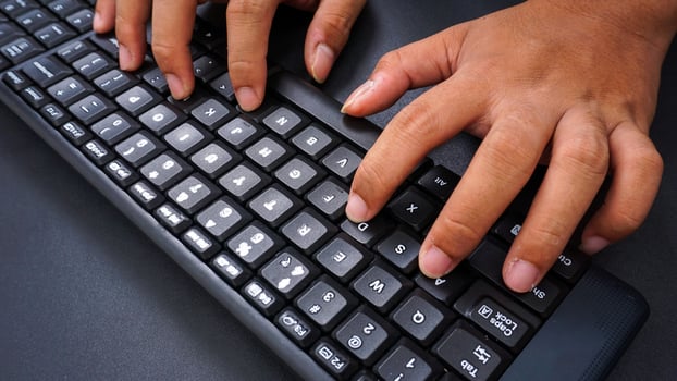Finger texting on a computer keyboard isolated on black background photo