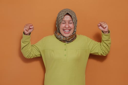 Excited Muslim woman celebrates achievement with energetic fists, ideal for success, motivation, empowerment, emotional expression, and positive lifestyle themes photo