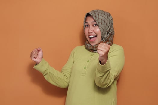 Happy Muslim woman excited with fist pump gesture showing success photo