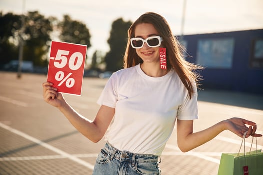Big sale. Beautiful woman in casual clothes is holding shopping bags, outdoors photo