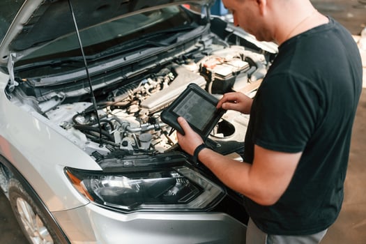 Holding the ,tablet. Man is works in the automobile repairing salon photo