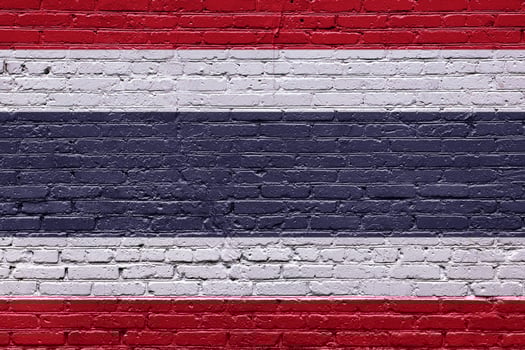 A textured brick wall with the flags of Thailand displayed photo