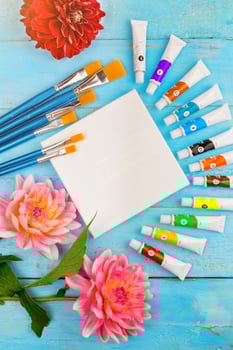 summer background. paints, brushes and a canvas on a blue wooden background. art. space for a text photo
