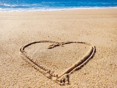 Heart drawn in sand at oceans edge. Represents love, romance, or vacation. Evokes feelings of happiness, relaxation, and connection. Ideal for travel, romance, or wellness themes. photo