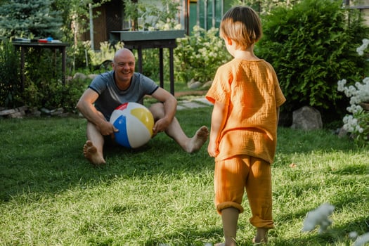 Summer outdoor activities. Father and son having fun playing with inflatable ball in backyard. photo