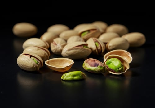 A close up view of pistachios on a black surface, some opened and some closed. photo