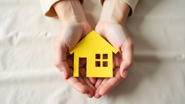 Hands Holding Yellow Paper House Symbolizing Home Insurance and Property Safety photo