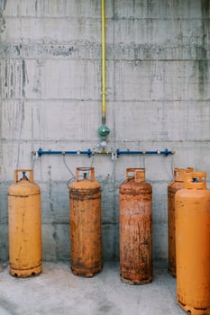 Orange gas cylinders connected to pipes on a concrete wall photo