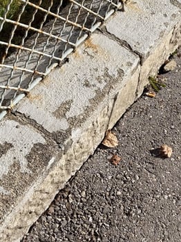 Weathered concrete and metal fence with fallen leaves on pavement photo