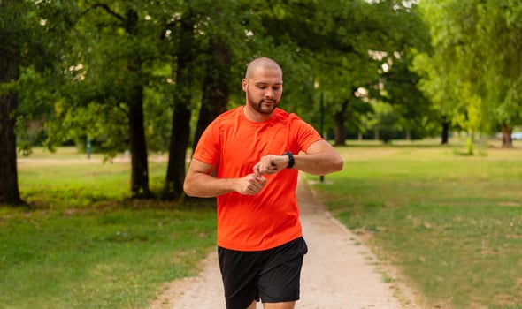 Sporty man running or jogging at the park active healthy lifestyle runner with fitness smart watch check running time. photo