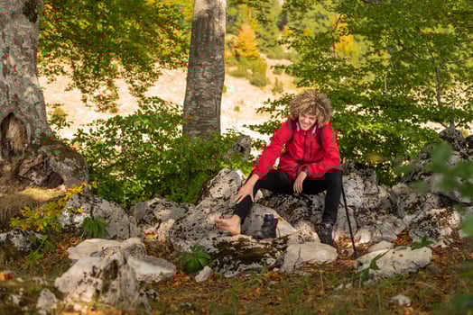 A male hiker solo explores a mountain forest, suffering from leg pain, injured during hiking trail. photo