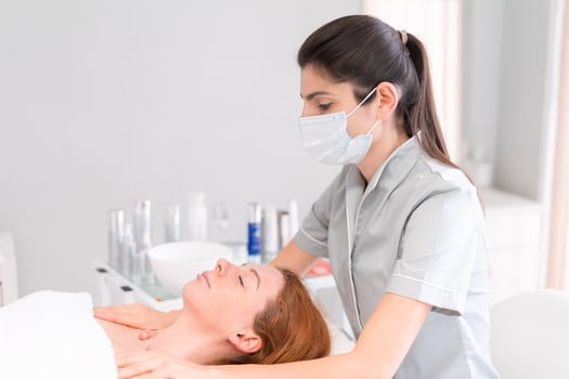 Cosmetologist in mask massaging woman shoulders at beauty salon photo