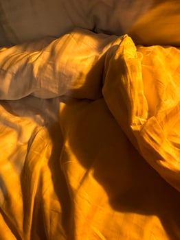 Soft golden light illuminates cozy bedding in a tranquil bedroom setting photo