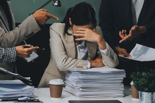 A woman is holding her head in her hands while surrounded by piles of papers photo