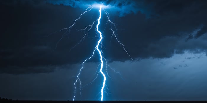 Electric blue lightning bolt strikes down from the dark sky illuminating the ground with energy and power photo