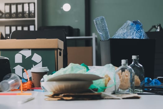 A desk with a trash can, recycling bin, and other items photo
