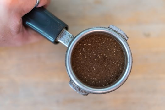 Close up of hands holding ground espresso in portafilter photo