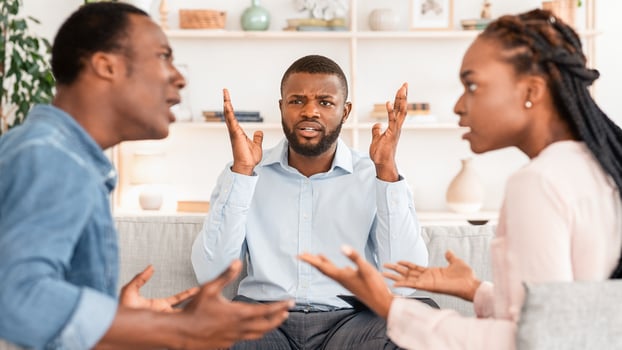 Annoyed black psychologist watching couple arguing during marital therapy session, can not manage conflict, african american spouses quarreling in front of family counselor, selective focus photo