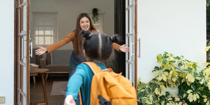 Excitement of Reunion and School Beginnings. A young girl runs towards her mother with open arms after the school day. photo