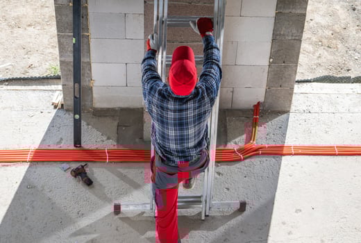 Construction Worker Climbing a Ladder During Brick Wall Installation photo