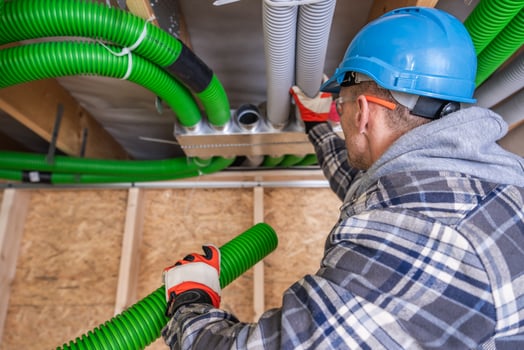Professional Worker Installing Green Ventilation Ducts Indoors photo
