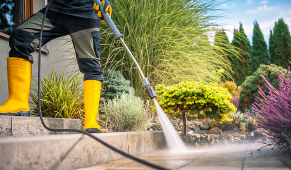 Person Using Pressure Washer for Outdoor Cleaning on Sunny Day photo