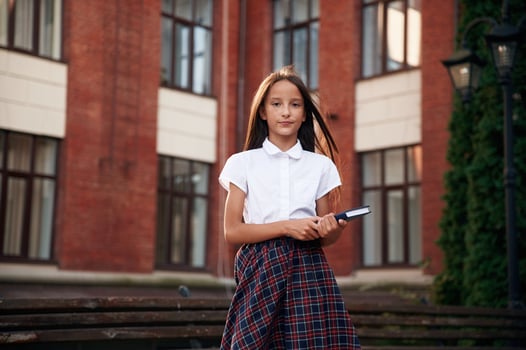 Orange colored ,building. School girl in uniform is outdoors photo