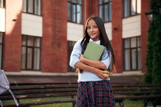 In ,uniform, against building. School girl is outdoors photo