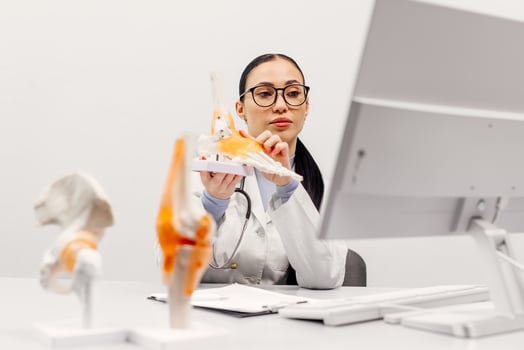An orthopedic doctor at a medical conference or consults a patient online, showing details on an anatomical model. The concept of online counseling photo