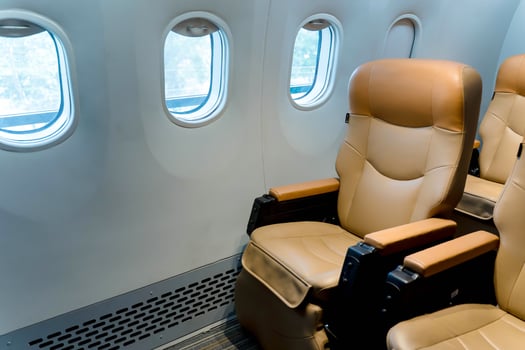Modern airplane cabin with empty beige leather seats beside window during daytime, comfortable travel and aviation concept interior photo