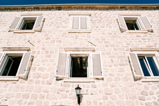 Facade of an old stone mansion with white wooden shutters wide open photo