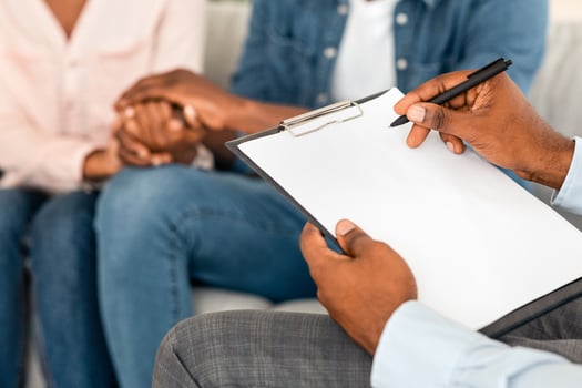 Marital Counselor Taking Notes At Therapy Session With African American Spouses, Holding Blank Clipboard, Filling Information Form At Marriage Counseling Meeting With Blank Couple, Cropped Image photo