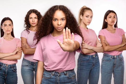 Determined Black Woman Gesturing Stop Protecting Group Of Multiracial Ladies Standing Over White Background, Studio Shot. Say No To Sexual Harassment, Protest And Forbidding Concept photo