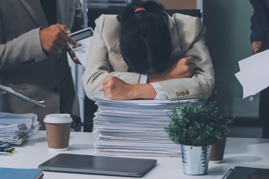 A woman is holding her head in her hands while sitting at a desk photo