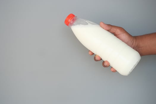 Holding a bottle of fresh milk against a neutral background photo
