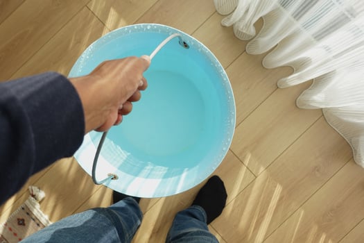 Person holding a blue bucket filled with water indoors photo