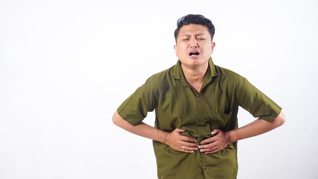 Asian man touch his stomach due to stomach ache isolated on white background photo