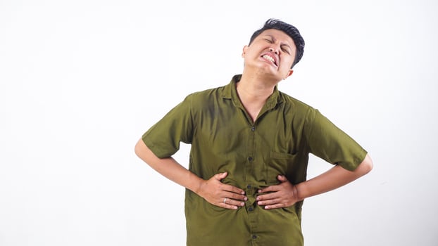 Asian man holding his stomach in pain from stomach ache isolated on white background photo