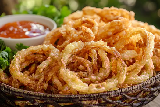 A basket of onion rings with a dipping sauce photo