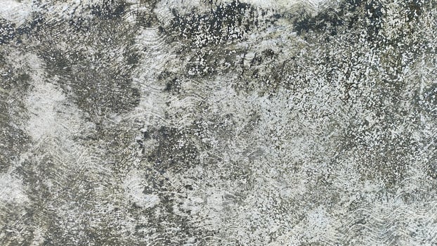 A weathered concrete wall with moss growing on the plaster cement, showcasing signs of age, nature, and decay, offering a rustic, natural aesthetic photo