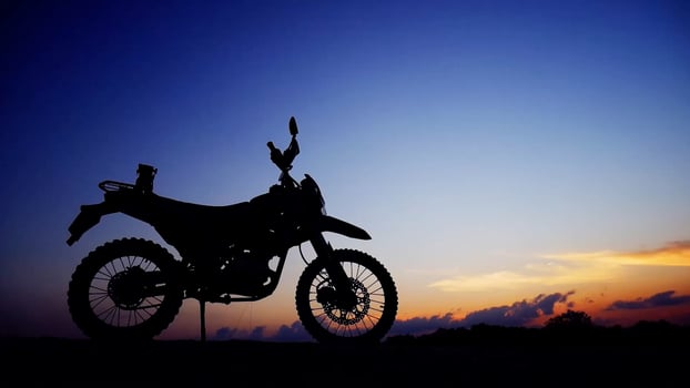 Silhouette of a Motorcycle Against a Vibrant Sunset Sky with Dramatic Clouds in the Background photo
