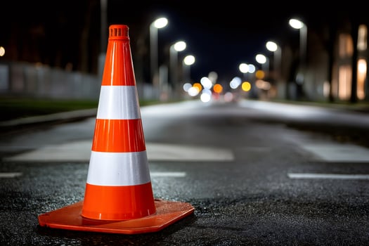 Orange and white traffic cone standing on asphalt road at night photo