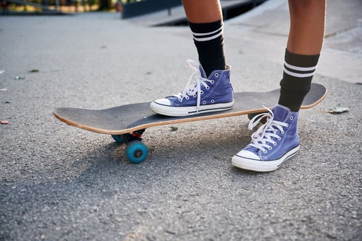 Standing on skateboard on one leg., Close up view of a young girl legs in blue shoes photo