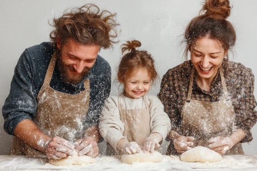 Cheerful family baking together with flour in air, creating dough on clean white background photo
