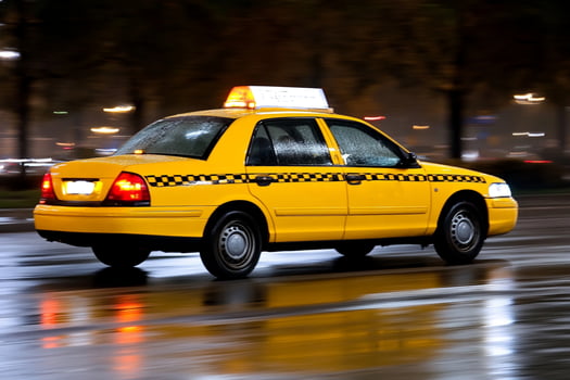 A taxi cab driving down a wet street at night photo
