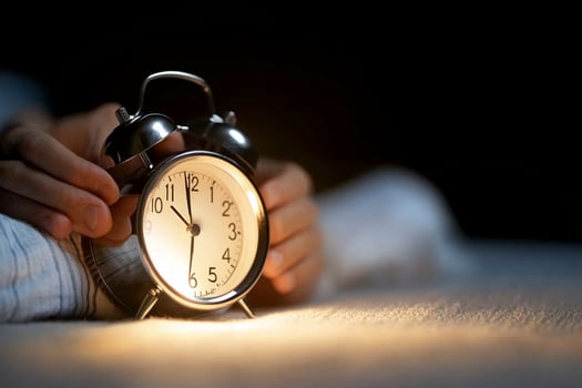 A person is holding an alarm clock in the dark photo