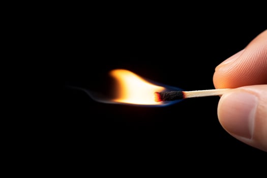 A person holding a matchstick with a lit match photo