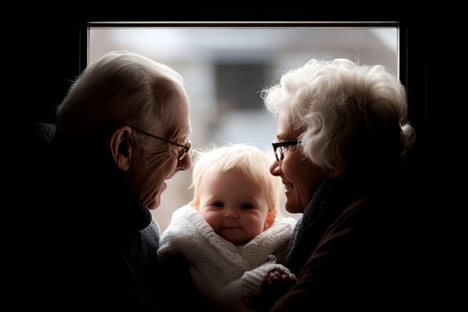 An older couple and a baby look out the window photo